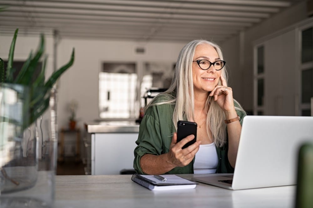Senior sitting in front of computer on the phone