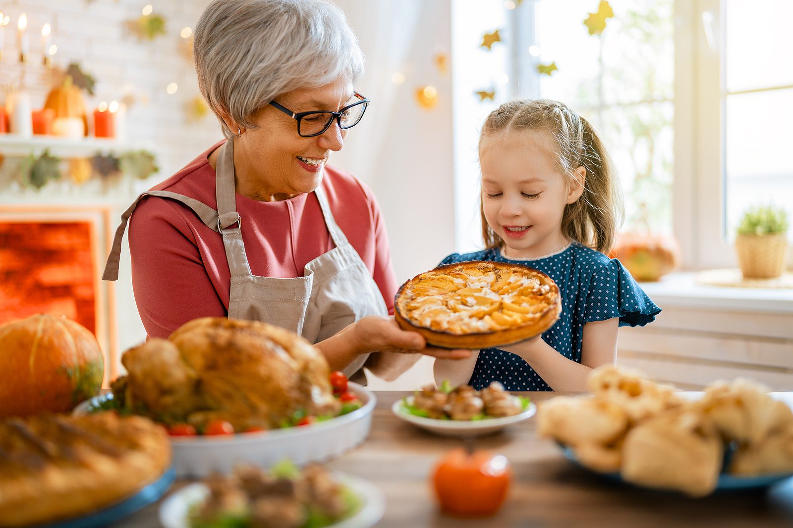 Older adult woman and her young granddaughter make a pie together to celebrate Thanksgiving
